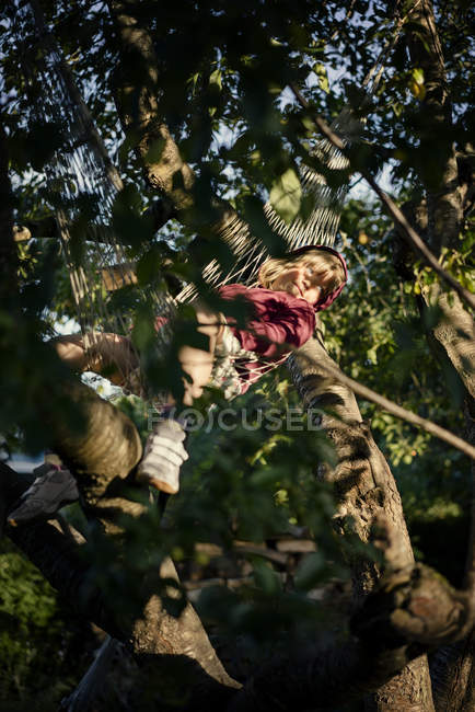 Menina com cabelo loiro deitado na rede na árvore — Fotografia de Stock
