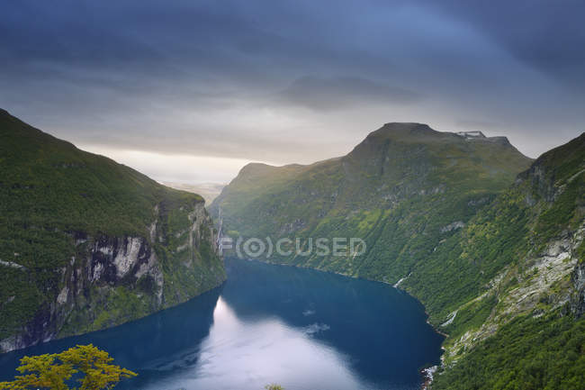 Вид на озеро і зелені покриті гори під хмарним небом — стокове фото