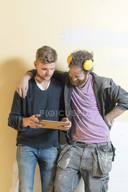 Друзья, использующие цифровой планшет во время ремонта — стоковое фото