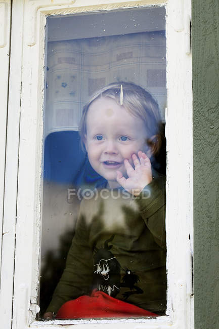 Frontansicht des Jungen, der durch das Fenster schaut — Stockfoto