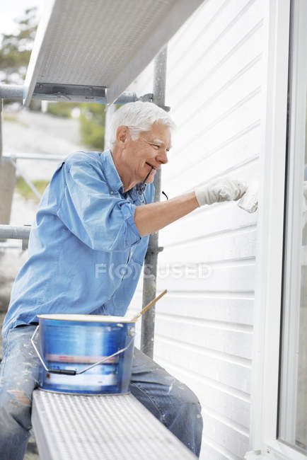 Sonriente hombre mayor pintura pared - foto de stock