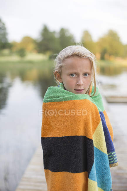 Retrato de niña envuelta en toalla después de nadar en el lago - foto de stock