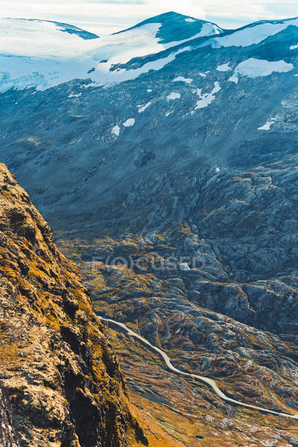 Route s'étendant à travers la vallée de montagne éclairée par le soleil — Photo de stock