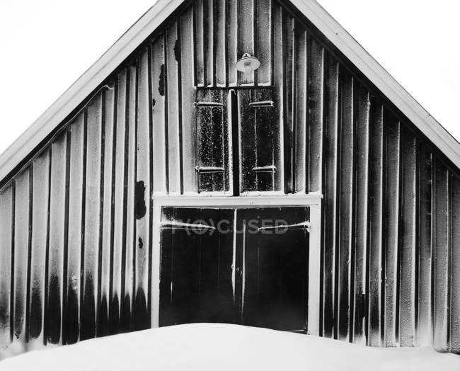 Vista frontal del granero cubierto de nieve, blanco y negro - foto de stock