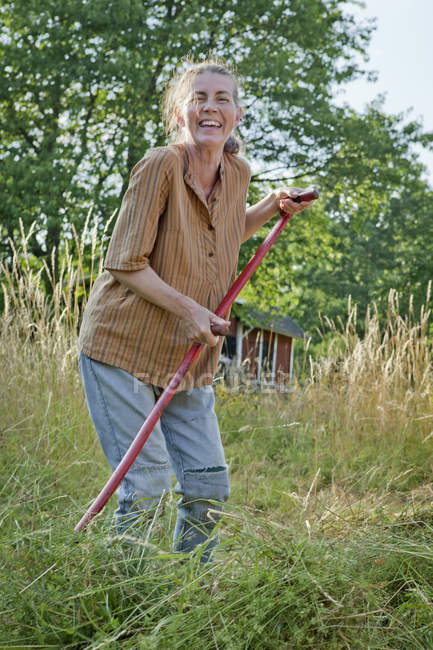 Agriculteur femelle coupe herbe à l'été — Photo de stock