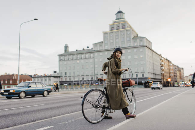 Donna che guarda oltre le spalle e in bicicletta sulla strada della città — Foto stock