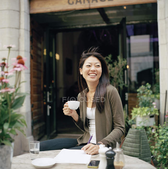 Mulher sorridente com xícara no café — Fotografia de Stock