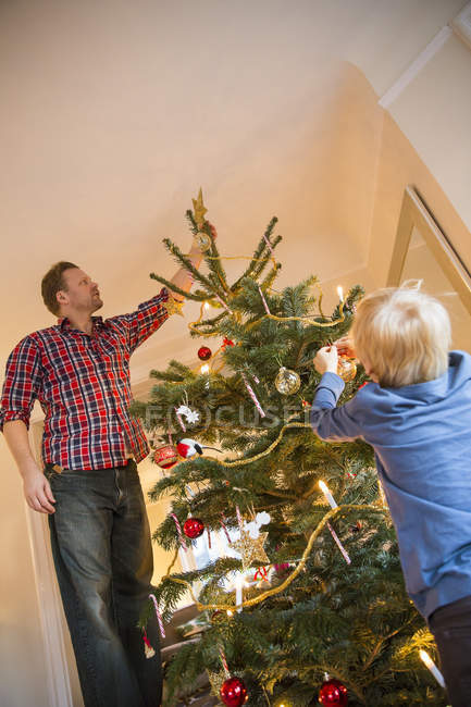 Padre e hijo decorando árbol de navidad - foto de stock