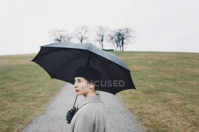 Portrait of woman holding umbrella outdoors — Stock Photo