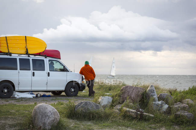 Rear view of Man looking at sailing boats in the ocean — Stock Photo