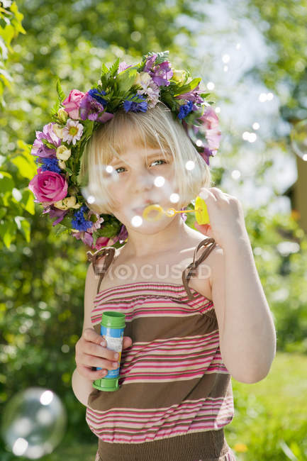 Girl blowing soap bubbles, focus on foreground — Stock Photo