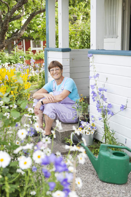 Woman sitting at front stoop of garden house — Stock Photo