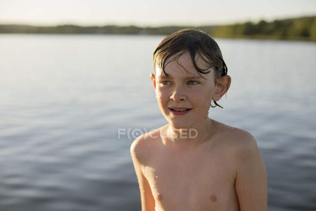 Vista frontal del chico mojado de pie junto al lago - foto de stock