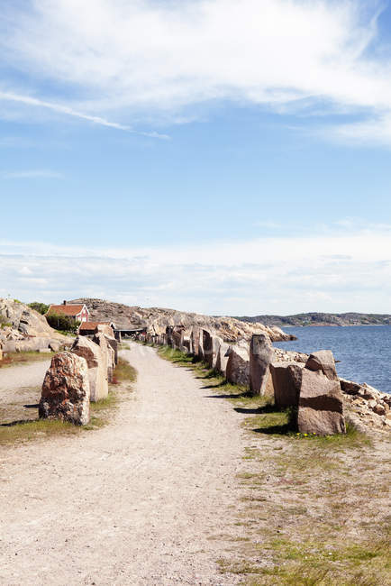 Camino con rocas a lo largo de la costa del mar bajo cielo azul - foto de stock