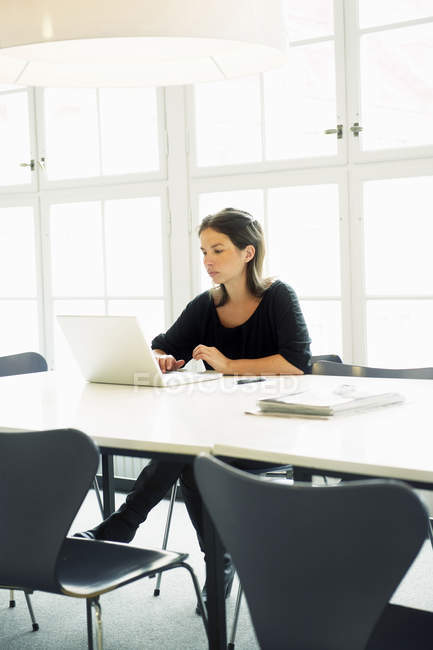 Young woman using laptop in office — Stock Photo
