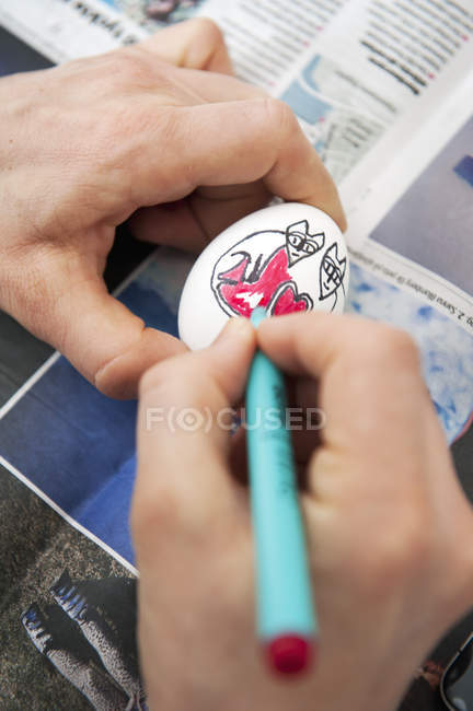Чоловічі руки розмальовки яєць з фетровою кінчиковою ручкою над газетою — стокове фото
