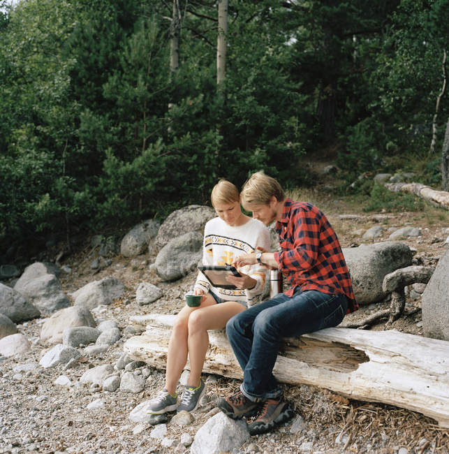 Couple utilisant une tablette numérique en forêt, se concentrer sur l'avant-plan — Photo de stock
