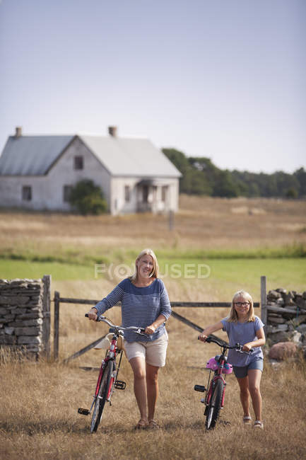 Bicicletas de rodas de mãe e filha na fazenda, foco diferencial — Fotografia de Stock