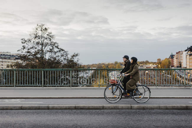 Мужчина и женщина катаются на велосипеде по улицам города, фокусируются на переднем плане — стоковое фото