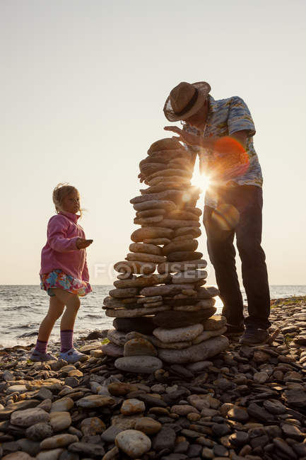 Grandfather and granddaughter making stone heaps — Stock Photo