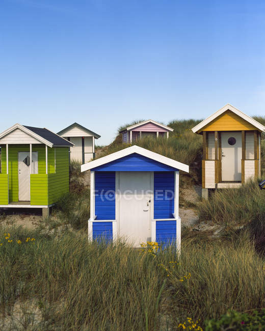 Bunte Hütten am grasbewachsenen Strand unter blauem Himmel — Stockfoto