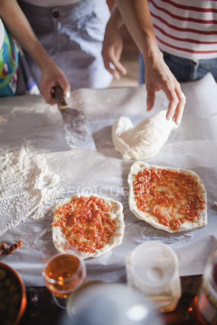 Two women preparing pizzas on table — Stock Photo