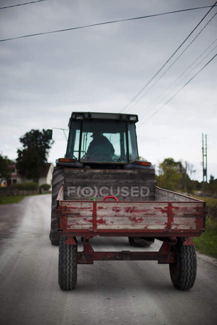 Задний вид человека за рулем трактора на дороге, выборочная фокусировка — стоковое фото