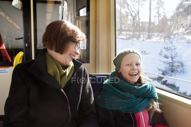 Girl sitting with grandmother in tram and laughing — Stock Photo