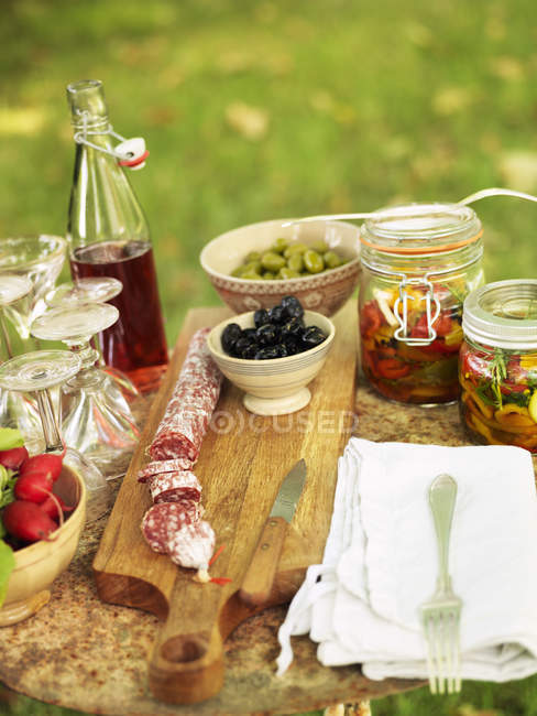 Bottle of syrup and pickled vegetables on table — Stock Photo