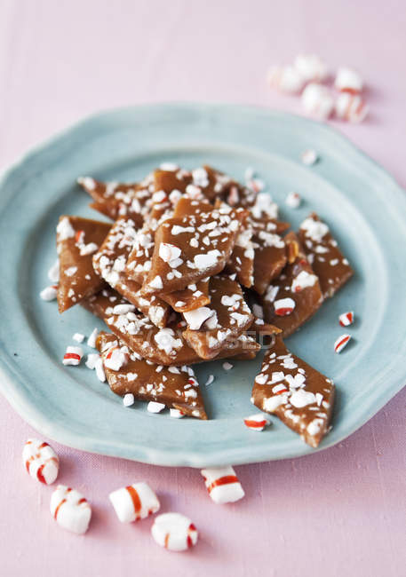 Crushed toffee and polkagris sweets on blue plate — Stock Photo