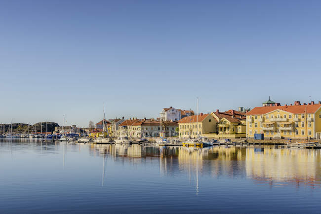 Houses and moored boats with blue sky reflecting in harbor water — Stock Photo