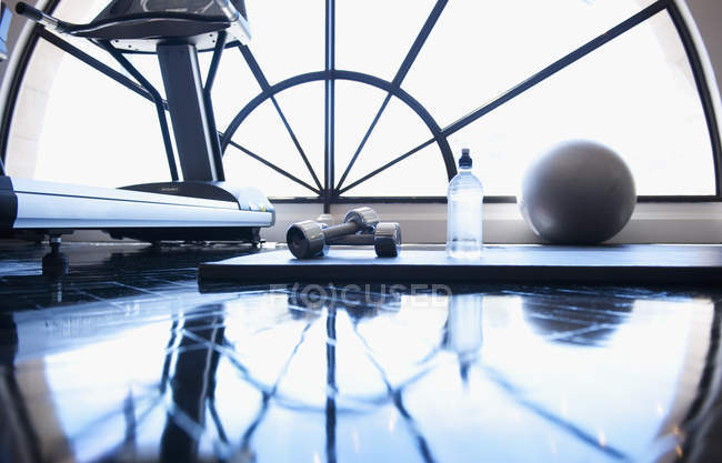 View of hand weights, ball and bottle of water at gym — Stock Photo