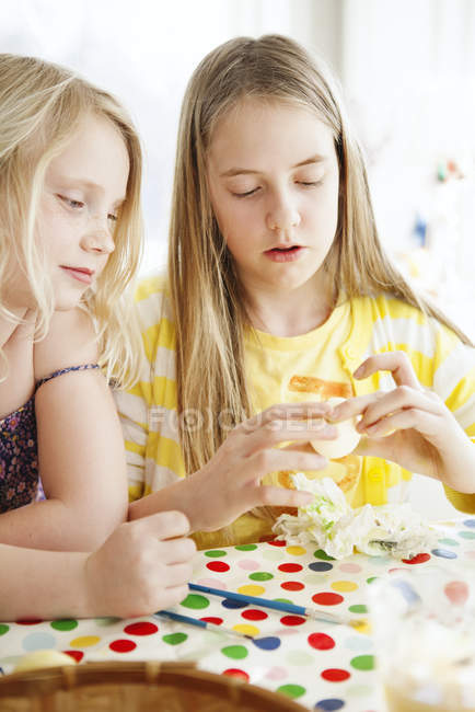 Girls painting eggs at kitchen, differential focus — Stock Photo