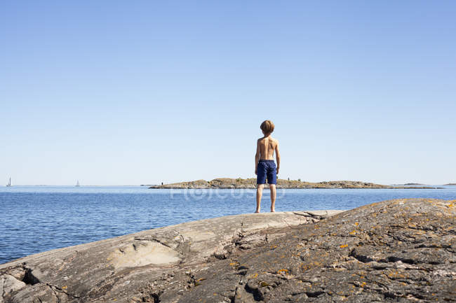 Vista trasera del niño mirando al mar - foto de stock
