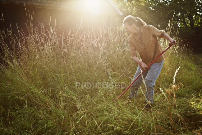 Vista laterale di agricoltore femminile taglio erba — Foto stock