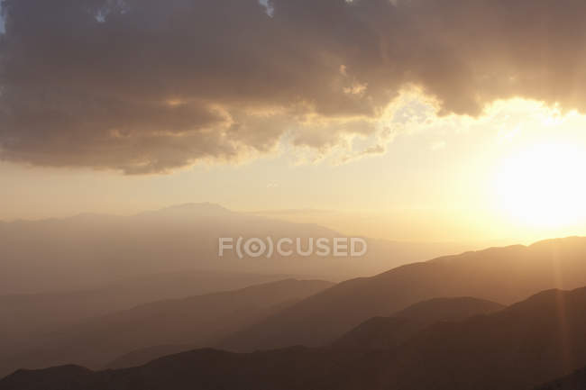 Bergsilhouetten und wolkenverhangener Himmel bei Sonnenuntergang — Stockfoto