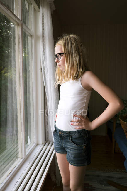 Chica mirando a través de ventana, enfoque selectivo - foto de stock