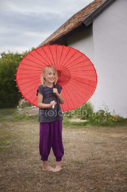 Girl with red parasol, focus on foreground — Stock Photo