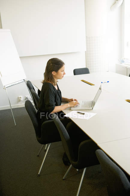 Jeune femme utilisant un ordinateur portable au bureau — Photo de stock