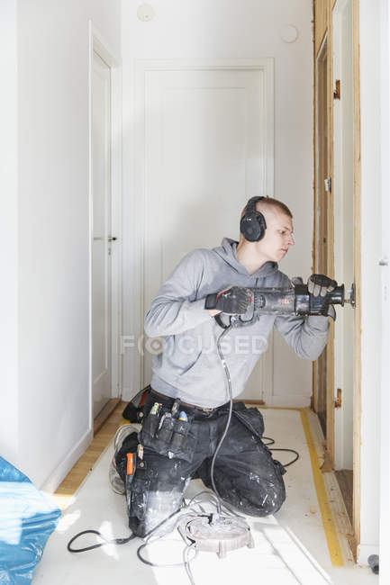 Junger Mann mit Ohrenschutz renoviert Haus — Stockfoto