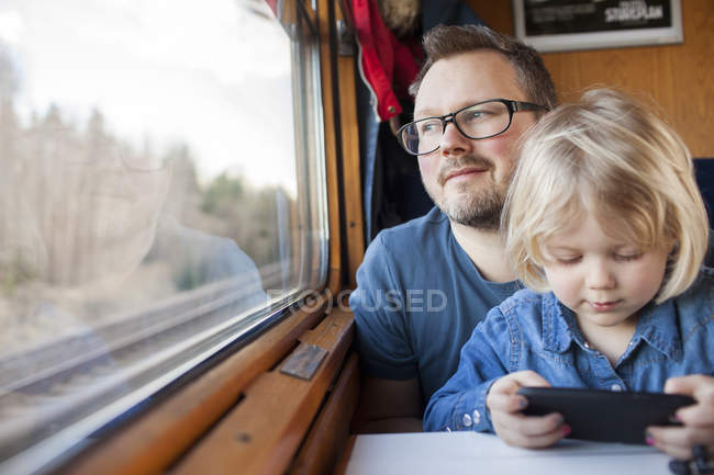 Father and daughter traveling by train and looking through window — Stock Photo