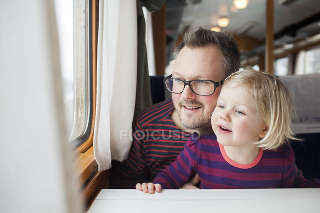 Vater und Tochter mit dem Zug unterwegs und schauen durch Fenster — Stockfoto