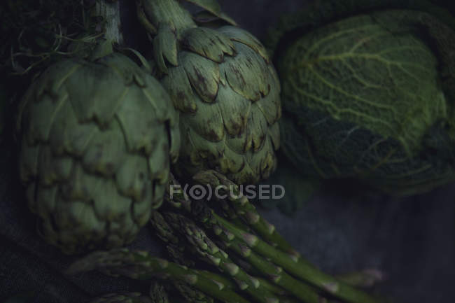 Fresh green artichokes, cabbage, asparagus and thyme on tablecloth — Stock Photo