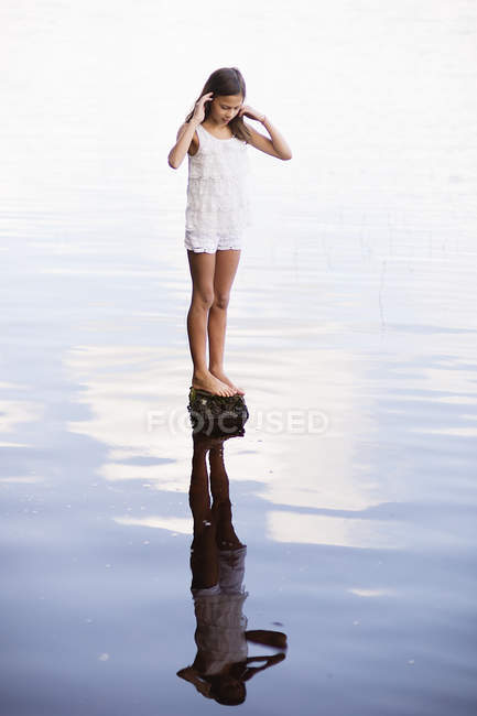 Ragazza con i capelli castani in piedi sulla roccia nel fiume — Foto stock