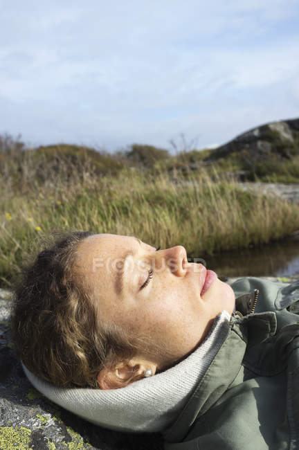 Femme adulte moyenne dormant au bord de la rivière, foyer sélectif — Photo de stock