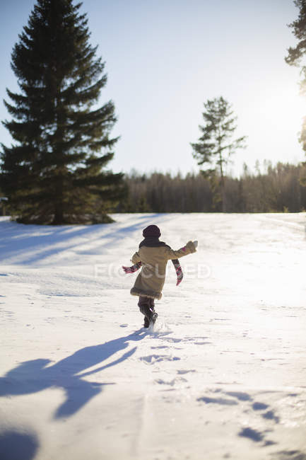Mädchen läuft an sonnigem Tag auf Schnee — Stockfoto