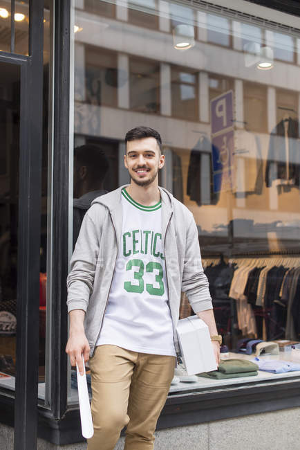 Человек, стоящий перед магазином одежды и смотрящий в камеру — стоковое фото