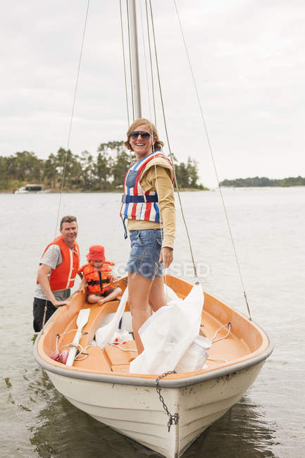 Сім'я з дитиною в рятувальних жилетах на вітрильному човні на річці — стокове фото