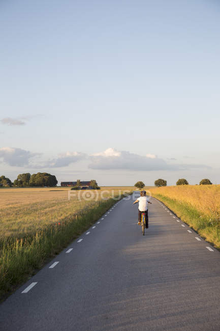 Boy riding bicycle on country road — Stock Photo