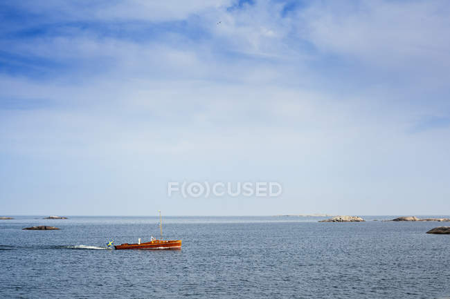 Лодка движется по морю под голубым облачным небом — стоковое фото